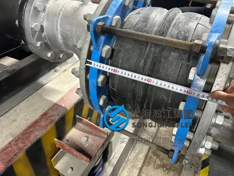Close-up technical detail of a high pressure double sphere rubber compensator installation focusing on structural steel control rods and heavy duty backing flanges