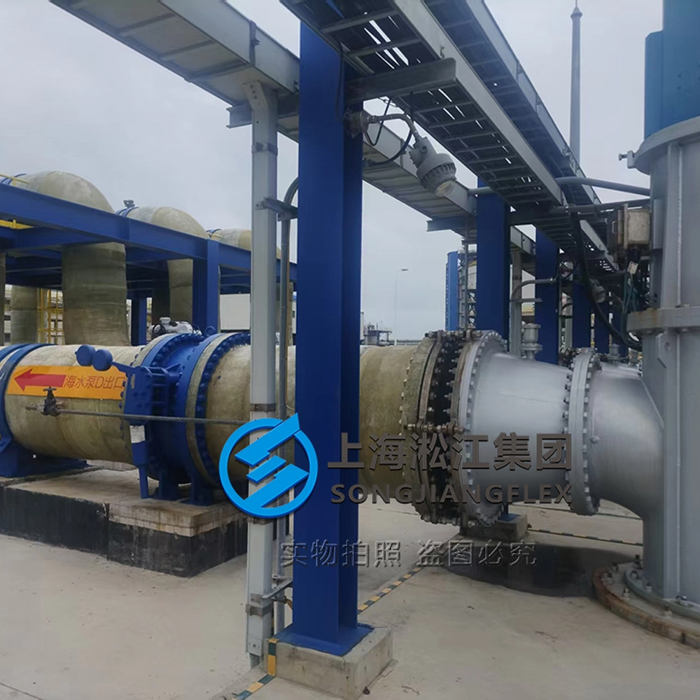 A heavy-duty large-diameter rubber expansion joint with hot-dip galvanized carbon steel backing flanges and control rods installed on a GRP seawater intake pump discharge piping system