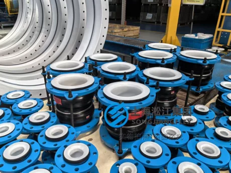 A batch of chemical-resistant rubber expansion joints featuring high-purity white PTFE liners, blue coated carbon steel flanges, and high-tensile control rod assemblies on a factory workshop pallet
